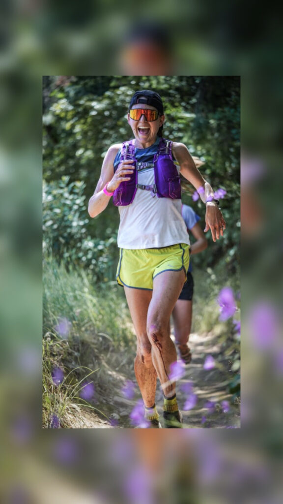 Katie Asmuth smiles as she runs down a wild flower lined trail.