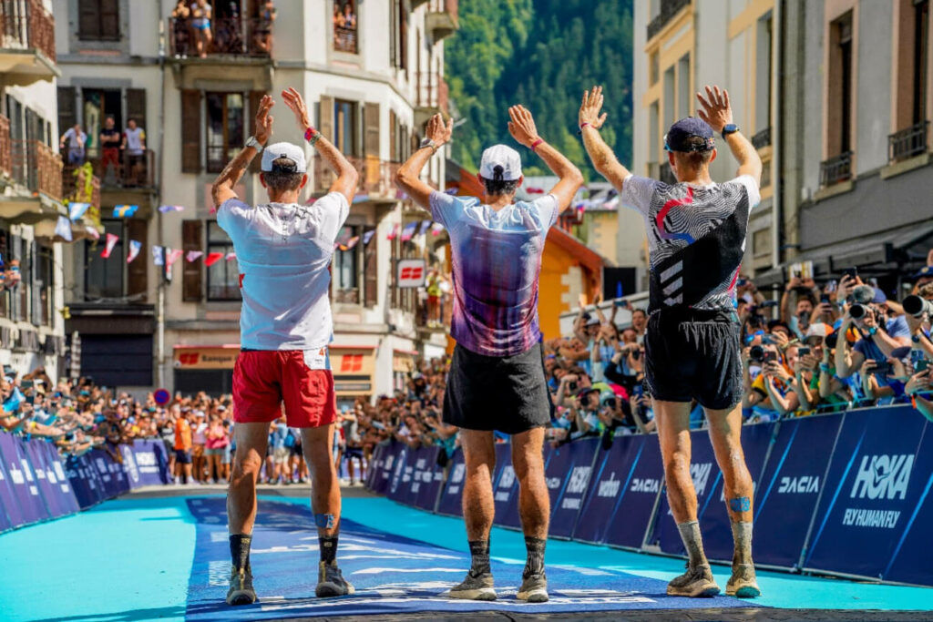 The top three men wave to the sea of fans at the finish line of UTMB in August of 2022